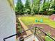 Serene backyard with lush green grass, mature trees, a garden bed, and outdoor seating at 3725 Fernwood Dr, Raleigh, NC 27612