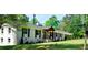 Beautiful one-story home with white brick, black shutters, and a covered front porch surrounded by lush greenery at 3725 Fernwood Dr, Raleigh, NC 27612