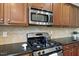Close-up of stainless steel gas range and microwave with granite countertops, and dark wood cabinets at 449 Sandy Whispers Pl, Cary, NC 27519