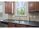 Cozy kitchen features a stainless steel sink, tiled backsplash, and wood cabinets beneath a bright window at 449 Sandy Whispers Pl, Cary, NC 27519
