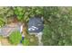 An aerial view of a two-story home featuring a black roof, a driveway and lush trees at 4500 Hollirose Pl, Raleigh, NC 27616