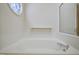 This is a large soaking tub with tiled walls and a decorative window at 4500 Hollirose Pl, Raleigh, NC 27616