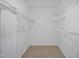 Walk-in closet with white wire shelving and neutral carpet flooring at 4500 Hollirose Pl, Raleigh, NC 27616