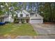 Inviting two-story home featuring white siding, green shutters, mature trees, and attached two car garage at 4500 Hollirose Pl, Raleigh, NC 27616