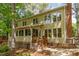 View of rear exterior of two-story home with wood siding, brick chimney and a small deck with wooden stairs at 53 Westridge Dr, Durham, NC 27713