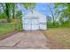 A stand-alone one car garage with white siding and a concrete driveway sits at the back of the home at 605 Dunbar St, Durham, NC 27701