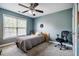 This bedroom features a ceiling fan, a window with blinds, and a bed with grey bedding at 6901 Rex Rd, Holly Springs, NC 27540