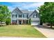 Charming two-story house boasts a well-kept lawn, mature trees, classic siding, and a two-car garage at 6901 Rex Rd, Holly Springs, NC 27540