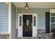 This charming home features a classic black front door and stone accents at 6901 Rex Rd, Holly Springs, NC 27540