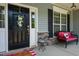 Inviting front porch features a chair, mosaic table, black door with a decorative wreath, and stone accents at 6901 Rex Rd, Holly Springs, NC 27540