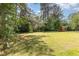 Spacious backyard with lush green grass, mature trees, and a shed for outdoor storage at 722 E Pine Ave, Wake Forest, NC 27587