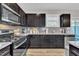Modern kitchen with stainless steel appliances, dark cabinets, gray backsplash and granite countertops at 743 Hadstock Path Path, Zebulon, NC 27597