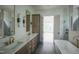 Bright bathroom featuring double vanity with marble countertop, gold fixtures, and open doorway to bedroom at 7805 Ailesbury Rd, Wake Forest, NC 27587