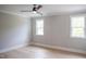 Bright bedroom featuring hardwood floors, ceiling fan, and two windows offering natural light at 7805 Ailesbury Rd, Wake Forest, NC 27587
