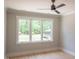 Cozy bedroom with hardwood floors, three large windows, a ceiling fan and exterior view at 7805 Ailesbury Rd, Wake Forest, NC 27587