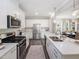 Bright kitchen featuring white cabinets, stainless steel appliances, quartz countertops, and modern lighting at 1000 Sora Way, Durham, NC 27703