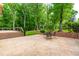 Spacious stamped concrete patio featuring a brick retaining wall, table, chairs, and a deck with stairs leading to a lush backyard at 101 Easton Ct, Garner, NC 27529