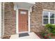 Close-up featuring the front door with beautiful stone surround and manicured landscaping at 1073 Branch Line Ln, Apex, NC 27502