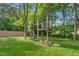 Wood playground structure with swing and treehouse in large backyard with lush green grass at 1207 Candlewood Dr, Elon, NC 27244