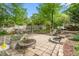 Stone patio with fire pit and sitting area in a backyard with mature trees and landscaping at 1207 Candlewood Dr, Elon, NC 27244