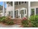 Charming front porch with brick steps, floral accents, and a welcoming entrance framed by potted plants at 1207 Candlewood Dr, Elon, NC 27244