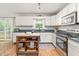 Well-lit kitchen featuring white cabinets, wood floors, and a view to the deck at 1207 Candlewood Dr, Elon, NC 27244