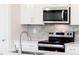 Modern kitchen features stainless steel appliances, gray tile backsplash, and stylish chrome water faucet at 147 Little Crk Dr, Lillington, NC 27546