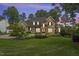 Inviting stone home with lush landscaping and warm exterior lighting at twilight at 1605 Hunting Ridge Rd, Raleigh, NC 27615