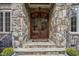 Elegant stone entryway with a custom double-door entrance and iron railings at 1605 Hunting Ridge Rd, Raleigh, NC 27615