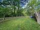 Spacious backyard featuring a wooden fence, mature trees, and lush green lawn at 1708 Sundial Pl, Raleigh, NC 27610