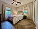 Sunlit bedroom with herringbone floors, ceiling fan, and views of the landscaped outdoors at 1708 Sundial Pl, Raleigh, NC 27610