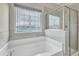 Soaking tub with window in a naturally lit primary bathroom with glass shower at 1844 Austin Ridge Pkwy, Wake Forest, NC 27587