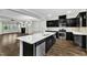 Open concept kitchen with black cabinets, stainless appliances, and quartz countertops overlooking the living area at 1844 Austin Ridge Pkwy, Wake Forest, NC 27587