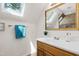 Bright bathroom featuring a skylight, a wood vanity, and decorative gold-trimmed mirror at 1915 Redding Ln, Durham, NC 27712
