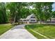 Two-story home with lush green yard and mature trees, showcasing a paved driveway and cozy front porch at 1915 Redding Ln, Durham, NC 27712