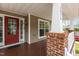 Cozy covered porch featuring white railings, brick pillars, and a painted wooden floor at 1928 Grace Point Rd, Morrisville, NC 27560
