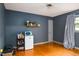 Bedroom with blue walls, wood floors, mini refrigerator, and window at 2021 Sunnybrook Dr, Burlington, NC 27215
