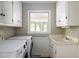 Laundry room with modern washer and dryer, white cabinets and a window at 2021 Sunnybrook Dr, Burlington, NC 27215
