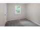 Cozy bedroom with neutral carpet, a window providing natural light, and a white door at 2222 Oak Ridge Blvd, Durham, NC 27707