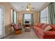 A living room with tan walls, carpet, large windows, ceiling fan, and a red sofa at 2503 Macdougall Dr, Burlington, NC 27217
