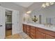 Bright bathroom with a double vanity, well-lit mirrors, and doorway view into the main bedroom at 2723 Cameron Pond Dr, Cary, NC 27519