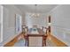 Bright dining room boasts hardwood floors, chair-rail detail, large window, and an elegant chandelier at 2723 Cameron Pond Dr, Cary, NC 27519