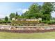 Inviting community entrance sign surrounded by colorful flowerbeds and well-manicured landscaping at 273 Scarlet Tanager Cir, Holly Springs, NC 27540
