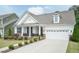 Charming white exterior showcasing a well-maintained lawn, inviting front porch, and attached two-car garage at 273 Scarlet Tanager Cir, Holly Springs, NC 27540
