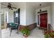 Cozy front porch with seating, decorative plants, brick accents, and a vibrant red front door at 273 Scarlet Tanager Cir, Holly Springs, NC 27540