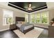 Main bedroom with tray ceiling, large windows, neutral colors, and dark wood floors at 273 Scarlet Tanager Cir, Holly Springs, NC 27540