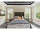 Main bedroom with a tray ceiling, large windows, neutral colors, and dark wood floors at 273 Scarlet Tanager Cir, Holly Springs, NC 27540