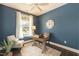 Bright office space with blue walls, a wooden desk, chair, and decorative clock at 273 Scarlet Tanager Cir, Holly Springs, NC 27540