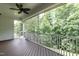 Covered porch with ceiling fan and wooded backyard view, accessible via screen door and staircase at 273 Scarlet Tanager Cir, Holly Springs, NC 27540