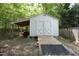 Exterior view of a white shed with double doors and a ramp for easy access, nestled in a wooded backyard at 320 Delvin Lane Ln, Hillsborough, NC 27278